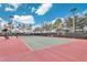 Outdoor tennis court featuring a red and green surface, surrounded by mature landscaping and black fencing at 4331 Arlington Ridge Blvd, Leesburg, FL 34748