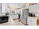A well-lit kitchen featuring white cabinetry, tile countertops, and stainless steel appliances at 4552 Cr 300, Lake Panasoffkee, FL 33538