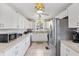 A well-lit kitchen featuring white cabinetry, tile countertops, and stainless steel appliances at 4552 Cr 300, Lake Panasoffkee, FL 33538