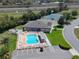 Aerial view of a community pool area with lounge chairs, a hot tub, and a recreational building in a well-kept setting at 6106 Kittiwake Dr, Lakeland, FL 33809