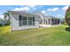 Backyard view showcasing the home's screened-in porch, pristine lawn, and mature landscaping at 613 Sherwood St, The Villages, FL 32162