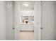 Hallway view of bathroom with double vanity, white cabinetry, and neutral tile floors at 613 Sherwood St, The Villages, FL 32162