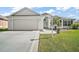 Charming one-story home featuring white siding, an attached garage, and a well-kept lawn at 613 Sherwood St, The Villages, FL 32162