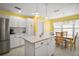 Bright kitchen with white cabinetry, an island, and a dining area by the window at 613 Sherwood St, The Villages, FL 32162