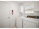 Laundry room featuring washer, dryer, window, overhead cabinet, and closet at 613 Sherwood St, The Villages, FL 32162