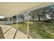 The covered patio area boasts brick flooring with a view of the big green lawn and mature trees at 7528 Park Hill Ave, Leesburg, FL 34748