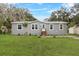 Inviting home showcases a manicured lawn, gray siding, and a neat entrance with small porch at 9060 Sarah Dr, Polk City, FL 33868