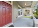 Inviting front porch featuring a red door and elegant white columns at 909 Egrets Landing Way, Groveland, FL 34736