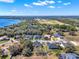 Aerial view of a neighborhood with waterfront homes surrounded by trees and bright blue skies at 9513 Mid Summer Ln, Leesburg, FL 34788