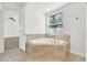 A luxurious bathroom featuring a tiled corner tub underneath a bright window at 9513 Mid Summer Ln, Leesburg, FL 34788