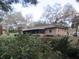 Back exterior view of the brick home surrounded by a green lawn and mature trees at 1009 Linda Glen Ave, Fruitland Park, FL 34731