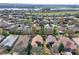 Wide aerial shot of a residential area with houses, trees, and a body of water in the background under a clear sky at 112 Flame Vine Way, Groveland, FL 34736