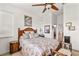 Bedroom with floral bedding, ceiling fan, side table and a view to the ensuite bathroom at 112 Flame Vine Way, Groveland, FL 34736