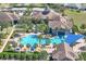Elevated view of a community pool area with a large pool, seating areas, palm trees, and a blue sunshade at 112 Flame Vine Way, Groveland, FL 34736