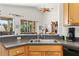 Kitchen sink with stainless fixtures, wood cabinets, and view into the living room at 112 Flame Vine Way, Groveland, FL 34736