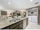 Open-concept kitchen featuring stainless steel appliances, granite countertops, and adjacent laundry area at 1131 Apple Ter, Leesburg, FL 34748