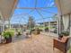 Screened lanai with tile flooring, seating, and a view of the lush landscaping at 1131 Apple Ter, Leesburg, FL 34748