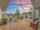 Screened lanai with tile flooring, seating, and a view of the lush landscaping at 1131 Apple Ter, Leesburg, FL 34748