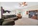 Spacious living room with plush carpet, fan, and a bookcase, adjacent to the kitchen at 11579 Acosta Ave, Orlando, FL 32836