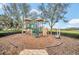 Community playground with a climbing structure, slide, and bench surrounded by trees at 11579 Acosta Ave, Orlando, FL 32836