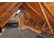 The attic is framed with exposed wooden beams, plywood walls, and a gray carpeted flooring at 12199 Se 175Th Loop, Summerfield, FL 34491