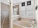 A tiled shower with a glass door, along with a soaking tub and plantation shutters at 12199 Se 175Th Loop, Summerfield, FL 34491
