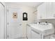 Bright laundry room with white cabinets, tiled floors, washer, dryer, and plenty of space for organizing household tasks at 12199 Se 175Th Loop, Summerfield, FL 34491
