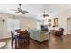 Open-concept living room with hardwood floors, ceiling fans, plantation shutters, and comfortable seating arrangement at 12199 Se 175Th Loop, Summerfield, FL 34491
