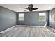 Bedroom with wood-look flooring, gray walls, ceiling fan, and two windows for natural light at 1301 N Shore Dr, Leesburg, FL 34748