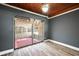 Bright living room features wood-look flooring, sliding glass door to screened patio, ceiling fan, and warm wood ceiling at 1301 N Shore Dr, Leesburg, FL 34748