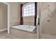 Bathroom featuring a bathtub beneath an arched window and a glass door shower at 1602 Oak Hollow Rd, Clermont, FL 34711