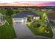 Beautiful aerial view of a house at dusk with manicured landscaping, driveway, and well lit entryways in Stonecrest at 17126 Se 117Th Cir, Summerfield, FL 34491