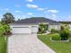 Landscaped front yard with a paver driveway leading to a three-car garage, and a beautifully maintained lawn at 17126 Se 117Th Cir, Summerfield, FL 34491