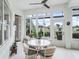 Sunroom with large windows overlooking landscaped backyard and a white table with cushioned chairs at 17126 Se 117Th Cir, Summerfield, FL 34491