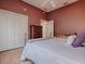 Comfortable bedroom featuring white linens, mauve walls, ceiling fan, and closet with door at 17694 Se 88Th Covington Cir, The Villages, FL 32162