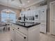 Well-lit kitchen island with granite countertops, white cabinetry, and stainless steel appliances at 17694 Se 88Th Covington Cir, The Villages, FL 32162