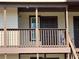Condo balcony with brown railings, tan siding, and view of the front door at 18203 Sandalwood Dr # 18203, Wildwood, FL 34785