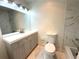 Bathroom featuring a gray vanity with a white countertop, framed mirror, toilet, and a shower with white marble-patterned tile at 18203 Sandalwood Dr # 18203, Wildwood, FL 34785