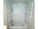Shower with white marble-patterned tile and a white bathtub at 18203 Sandalwood Dr # 18203, Wildwood, FL 34785