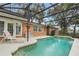 Relaxing in-ground pool within a screened enclosure, featuring a brick home exterior and lounge chairs at 1840 12Th St, Clermont, FL 34711