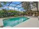 Refreshing in-ground pool with screened enclosure surrounded by lush landscaping and seating areas at 1840 12Th St, Clermont, FL 34711