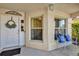 Inviting front porch with a white metal bench with blue cushions and a door with a decorative wreath at 1923 Greeleyville Ter, The Villages, FL 32162