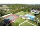 Aerial view of a tennis court, pool, and surrounding green lawns at 2065 Braxton St, Clermont, FL 34711