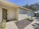 Front entrance featuring a neutral stucco exterior, a front door, and attached two-car garage at 2065 Braxton St, Clermont, FL 34711