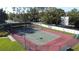 Aerial view of a well-maintained tennis court with lights, surrounded by a fence and trees at 2065 Braxton St, Clermont, FL 34711
