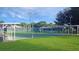 Outdoor tennis courts surrounded by green grass and shaded seating areas for players and spectators at 21410 Royal St Georges Ln, Leesburg, FL 34748