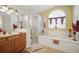 Bathroom featuring a soaking tub, a glass-enclosed shower, and a vanity with a marble countertop at 2471 Holly Berry Cir, Clermont, FL 34711