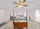 Cozy main bedroom featuring a four poster bed, ceiling fan, and private access to outdoor patio at 25013 Adair Ave, Sorrento, FL 32776