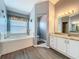 Bright bathroom featuring a soaking tub, marble countertop vanity, and a separate toilet room at 25110 Meriweather Rd, Leesburg, FL 34748