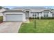 Charming single-story home featuring a well-maintained lawn, inviting entryway, and attached garage at 25110 Meriweather Rd, Leesburg, FL 34748